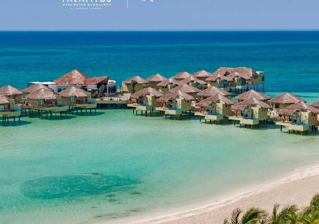 Stunning aerial view of overwater bungalows in turquoise waters at El Dorado Maroma, a luxurious beach getaway.