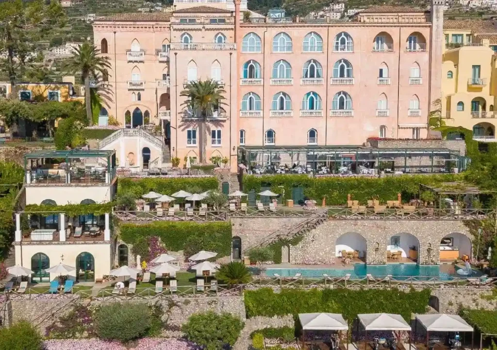 Luxurious hotel with stunning gardens, pools, and outdoor dining, set against a picturesque landscape. Ideal for relaxation.