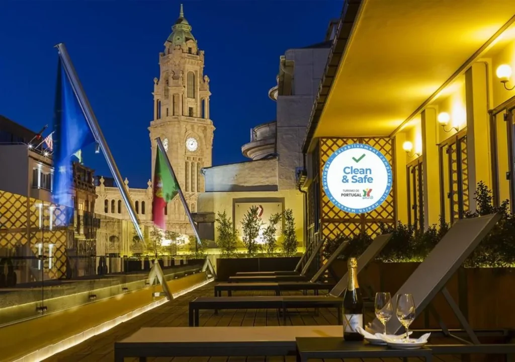 Stunning night view of a rooftop terrace with city clock tower, featuring a Clean & Safe certification in Portugal.