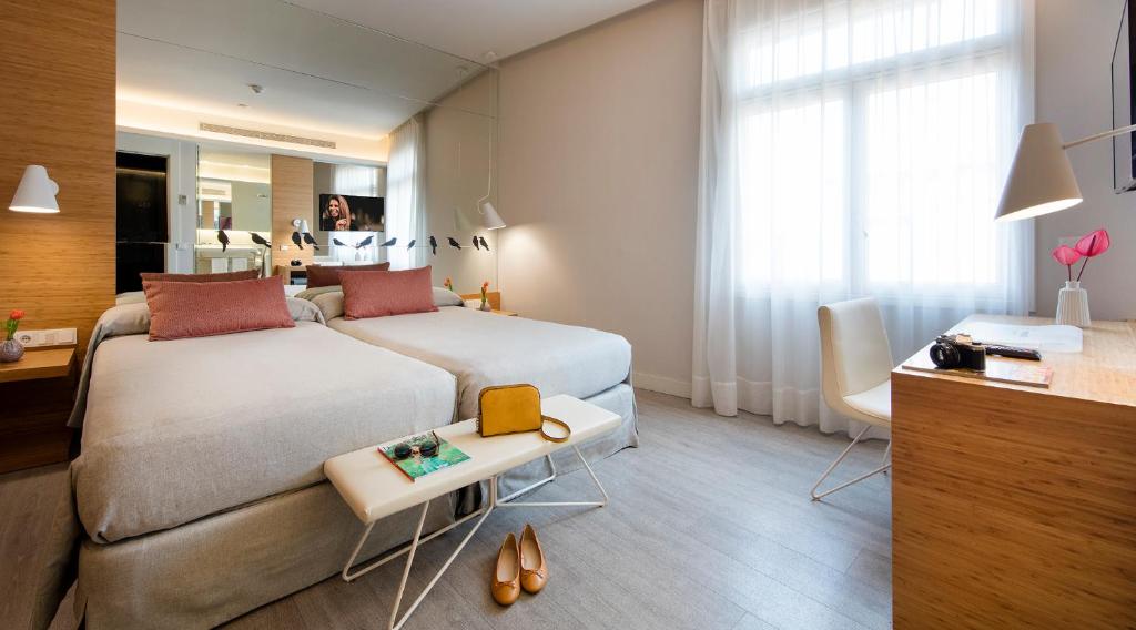 Cozy hotel room with two beds, modern decor, and a workspace, perfect for a comfortable stay.