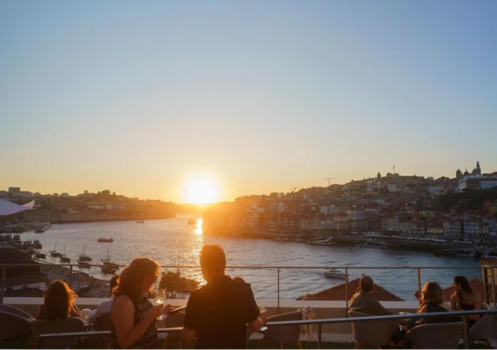 Charming sunset view over the river with people enjoying drinks on a terrace in a vibrant city. Perfect for relaxation.