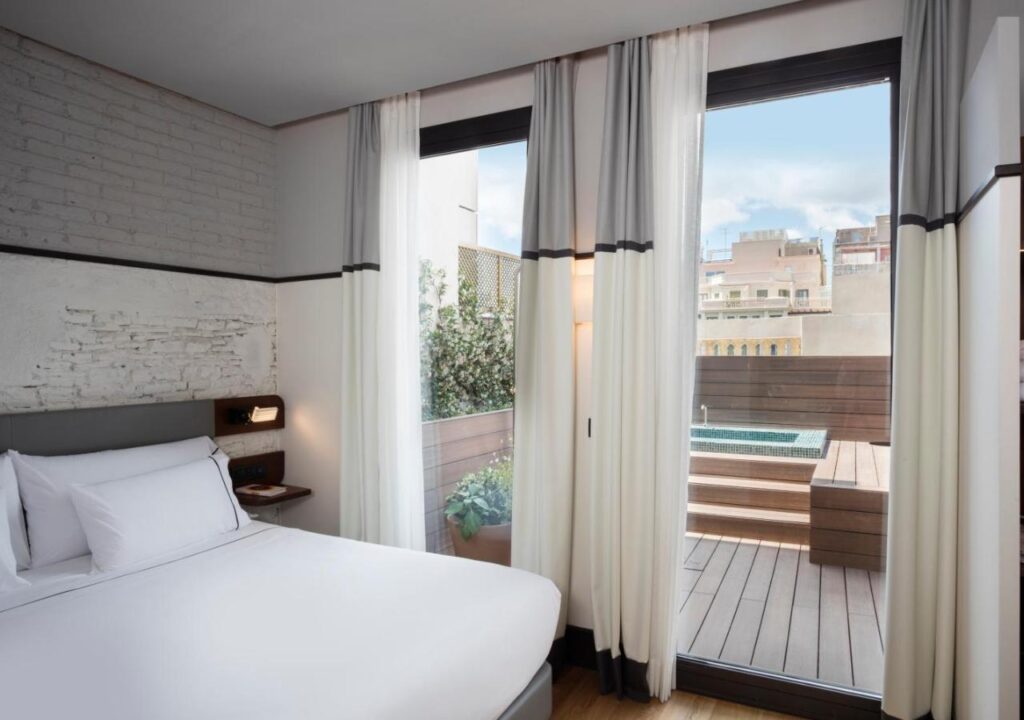 Cozy hotel room featuring modern decor, large windows, and a private terrace with a plunge pool. Perfect for relaxation.