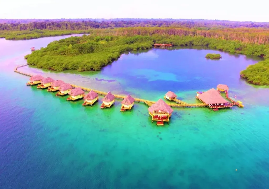 Aerial view of a tropical resort with overwater bungalows surrounded by turquoise waters and lush greenery.