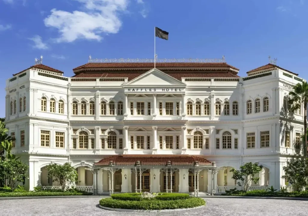 Alt text: Raffles Hotel, a historic colonial building in Singapore, showcasing elegant architecture against a blue sky.