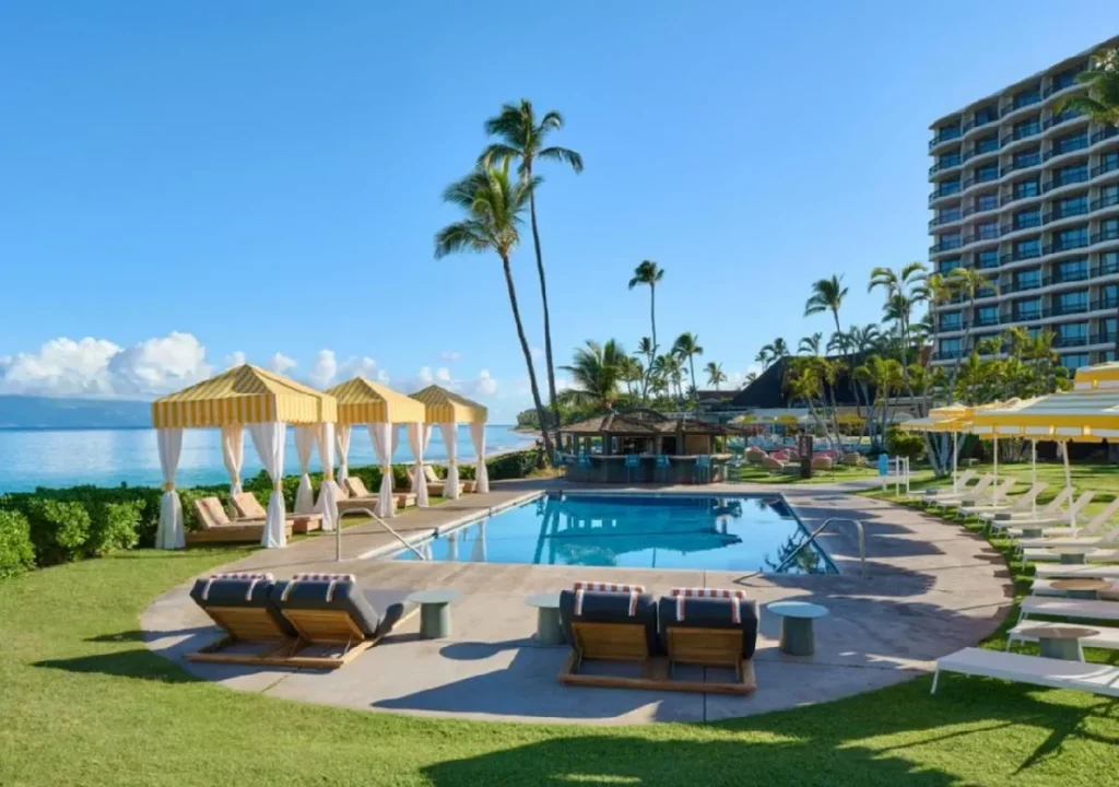 Luxurious resort poolside with sun loungers, cabanas, and palm trees overlooking the ocean, perfect for relaxation.
