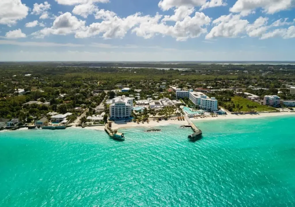 Aerial view of a tropical beach resort with clear turquoise water and lush greenery on a sunny day.