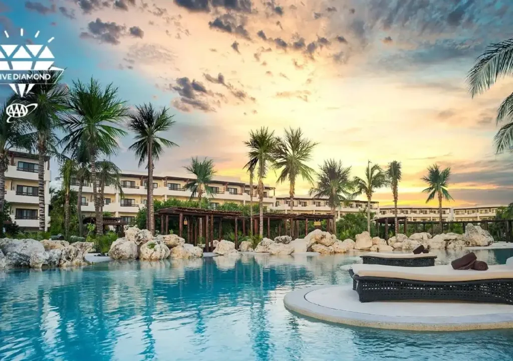 Luxurious resort pool at sunset with palm trees and modern architecture, offering a serene tropical getaway.