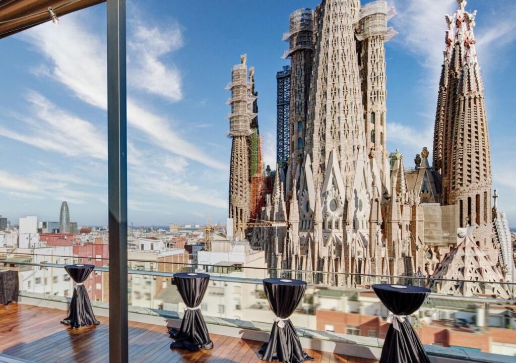 View of Sagrada Família, Barcelona skyline with elegant black tables on a balcony. A stunning architectural marvel.