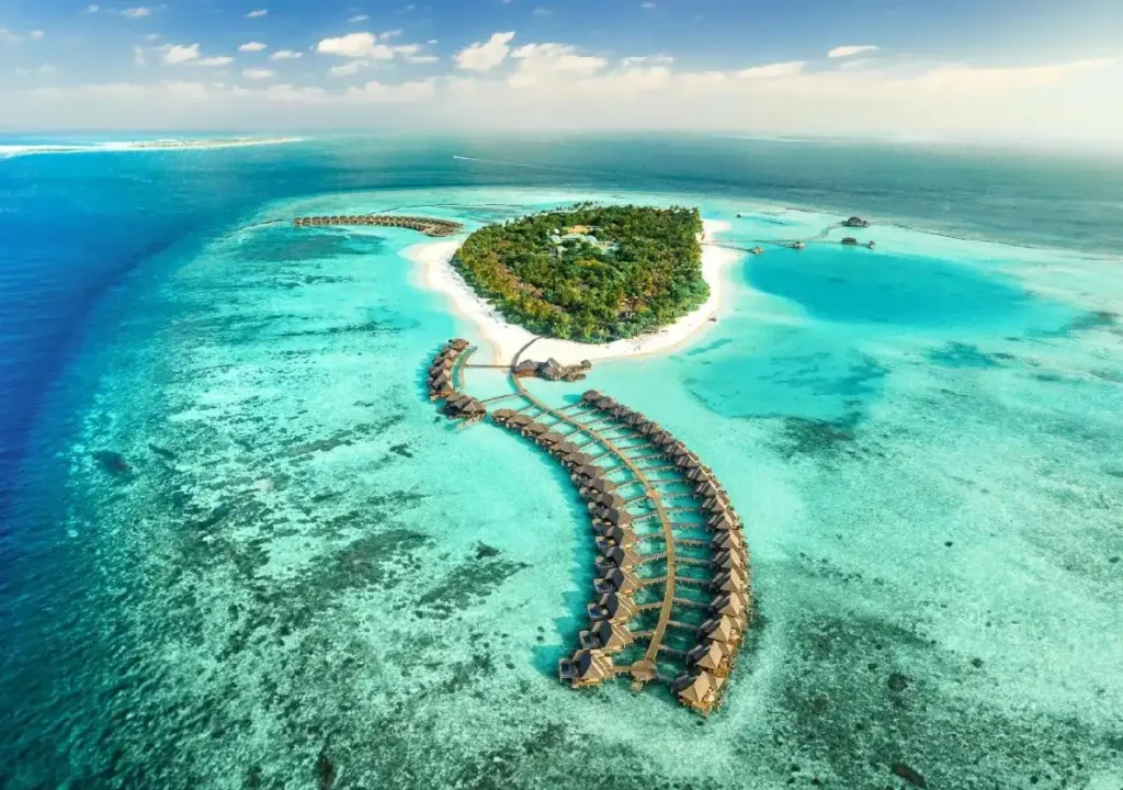 Aerial view of a tropical island with overwater bungalows and crystal-clear turquoise waters, perfect for a vacation.