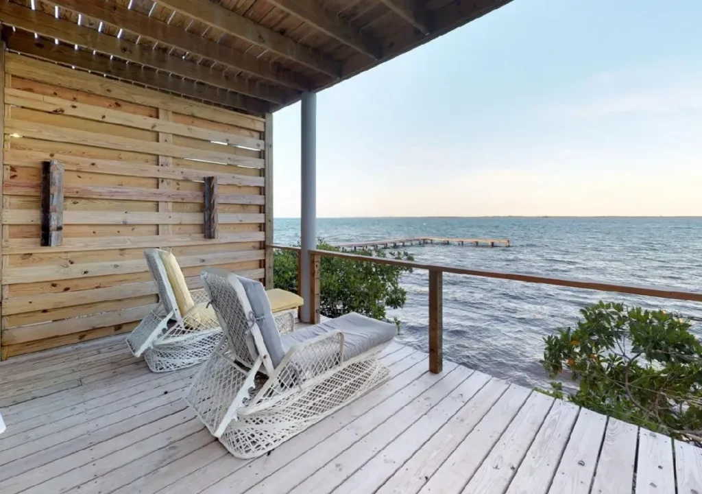 Serene waterfront view from a cozy porch with two reclined chairs, perfect for relaxation and enjoying nature.