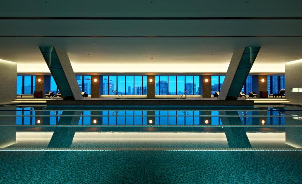 Elegant indoor pool with city skyline views, featuring modern architecture and serene lighting for a luxurious atmosphere.