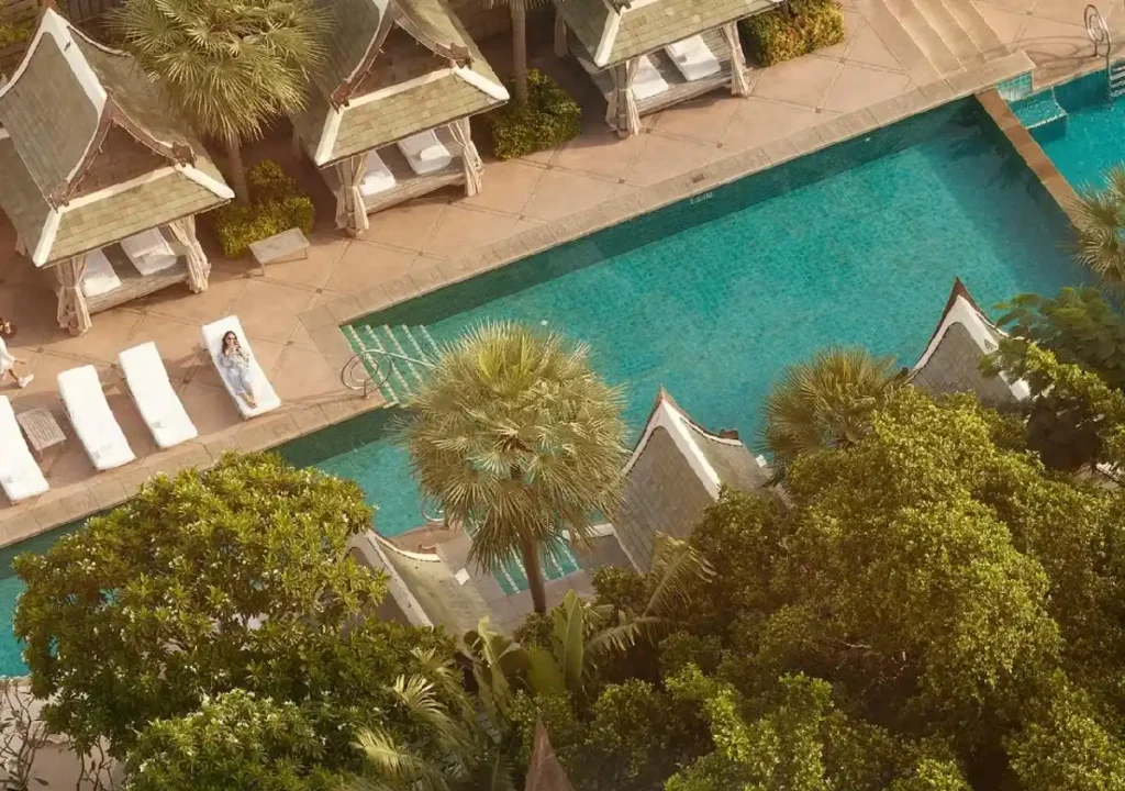 Luxurious resort poolside with private cabanas, sun loungers, and lush greenery for a serene getaway.