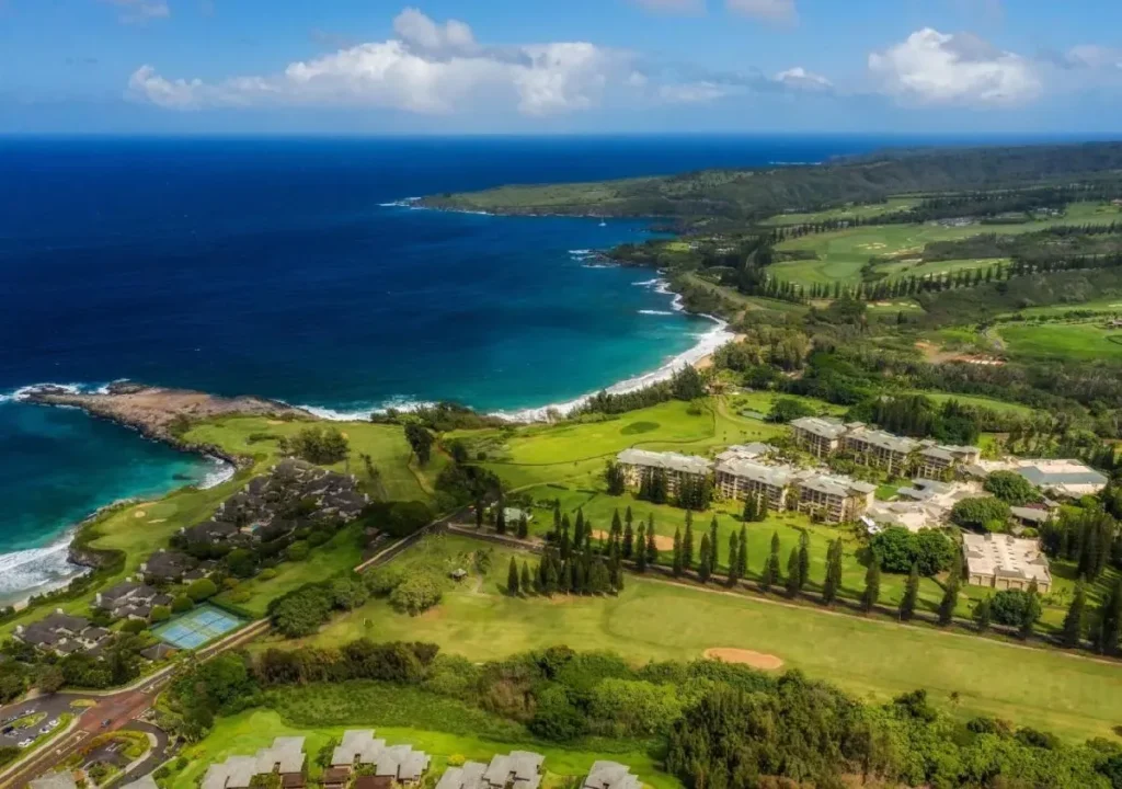 Aerial view of lush coastline, ocean, and green golf courses in a tropical paradise setting. Perfect for vacation planning.