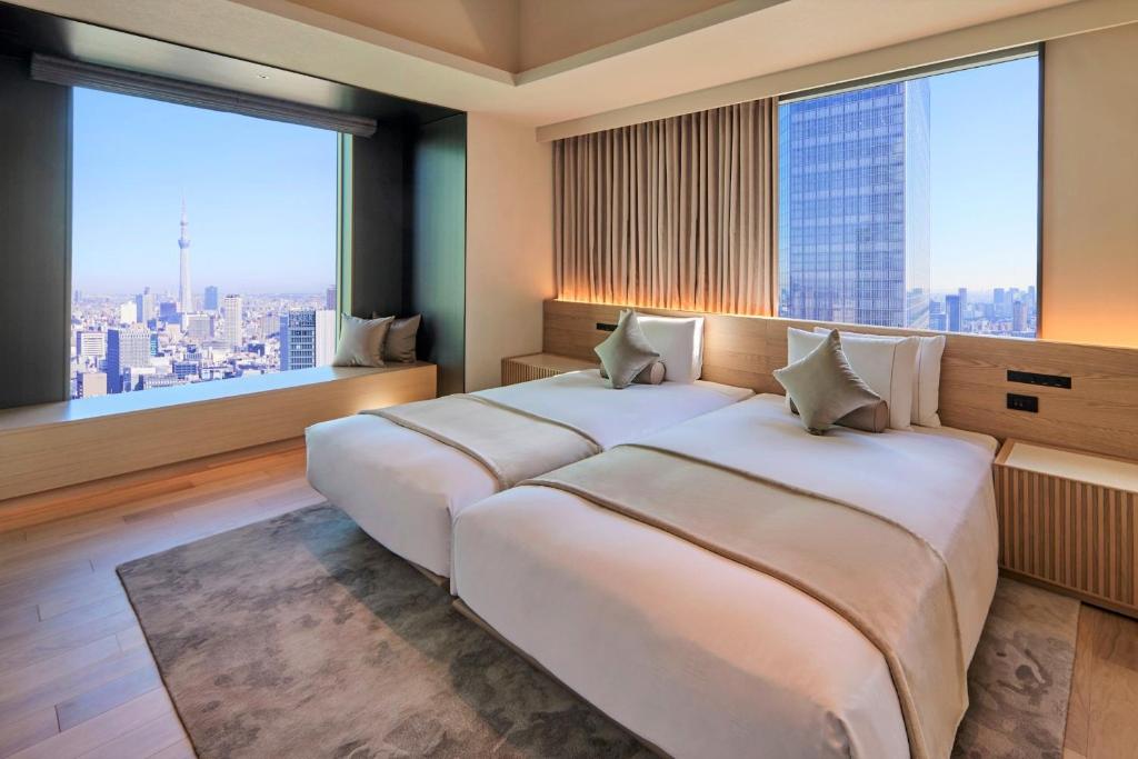 Modern hotel room with twin beds, elegant decor, and stunning city views featuring Tokyo Skytree in the background.
