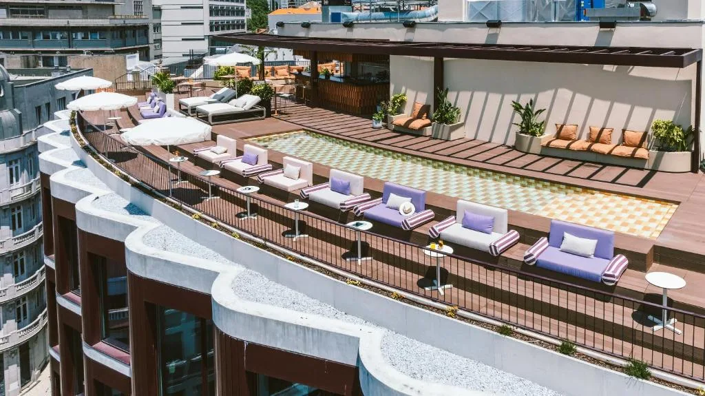 Rooftop pool area with lounge chairs and umbrellas, offering a relaxing urban escape and scenic city views.
