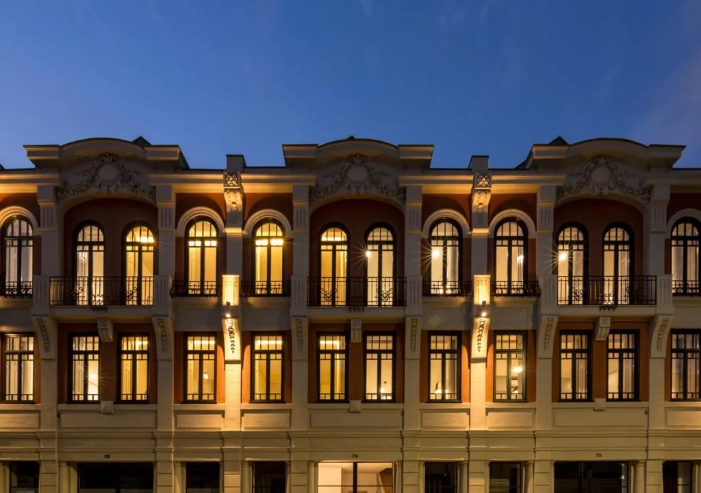 Elegant historic building facade illuminated at night, showcasing architectural details and large arched windows.