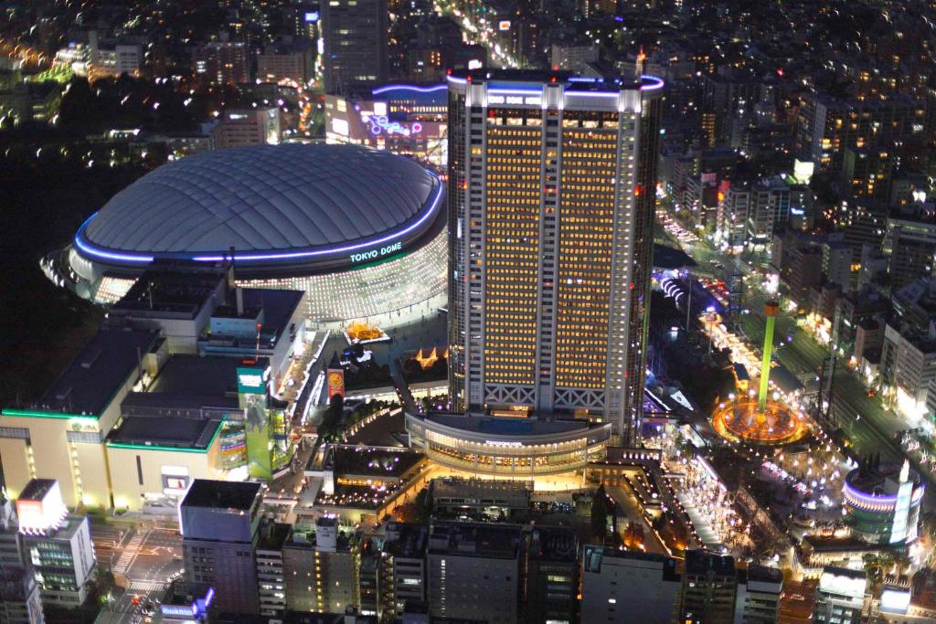 Aerial view of Tokyo Dome and urban nightlife, showcasing vibrant city lights and modern architecture.