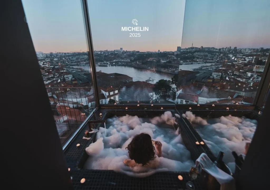 Person relaxing in a luxurious bubble bath with a stunning city view at sunset, representing wellness and leisure.