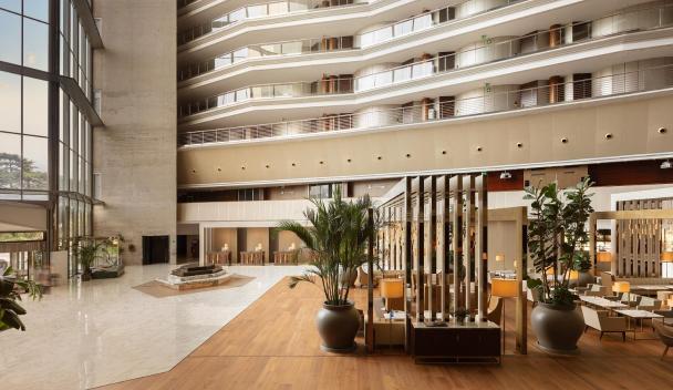 Modern hotel lobby featuring elegant decor, open space, and lush greenery, creating a welcoming atmosphere for guests.