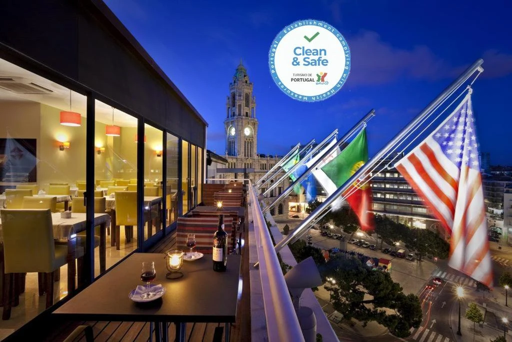 Outdoor dining area with city views, featuring flags and a 'Clean & Safe' certification emblem for traveler assurance.