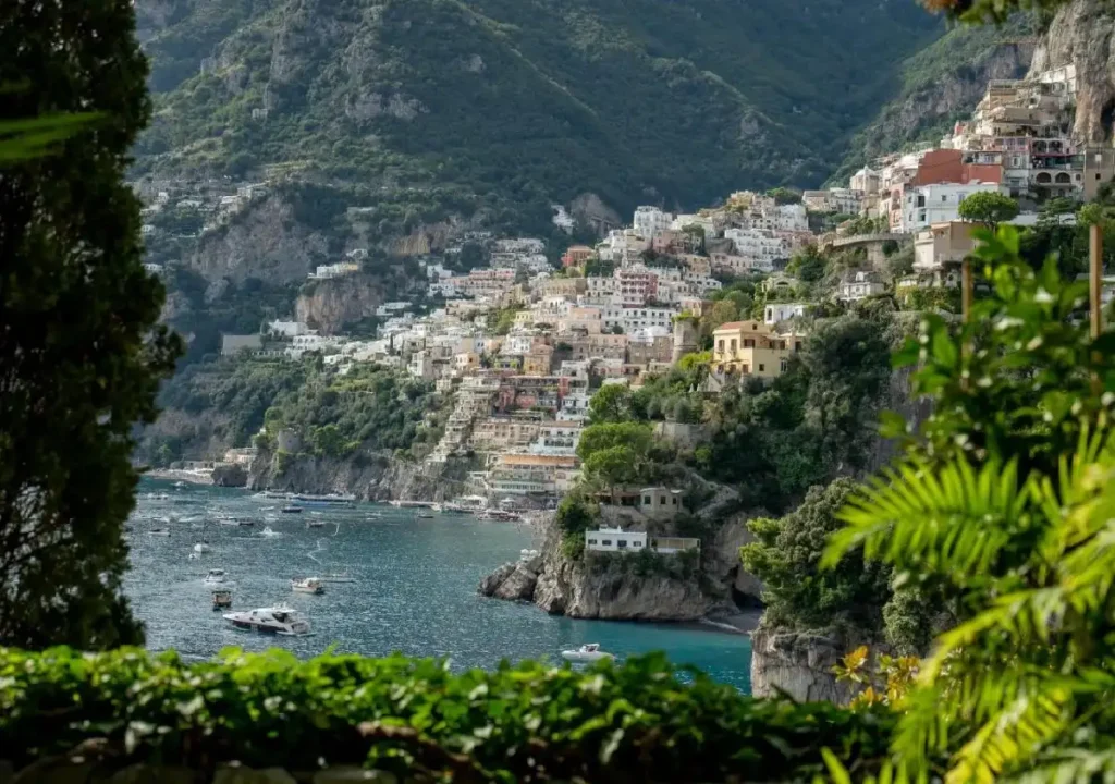 Scenic view of Positano on the Amalfi Coast, featuring colorful buildings, lush greenery, and boats on the serene water.