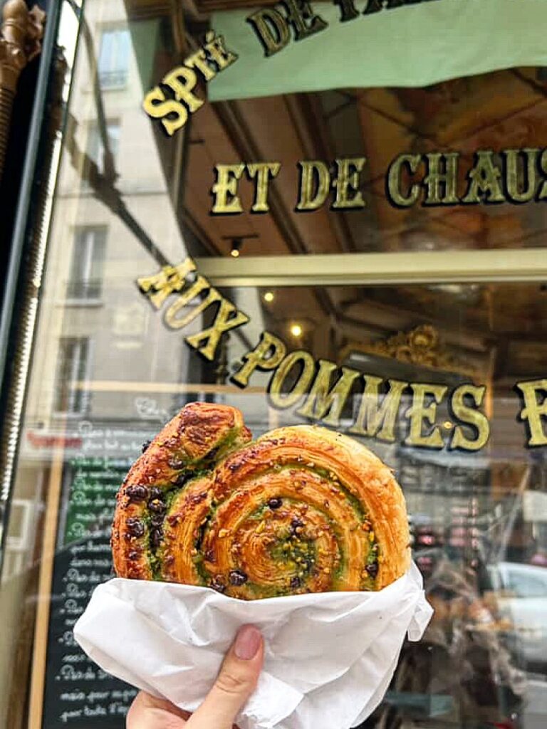 Fresh pistachio pastry in front of a French bakery shop window.