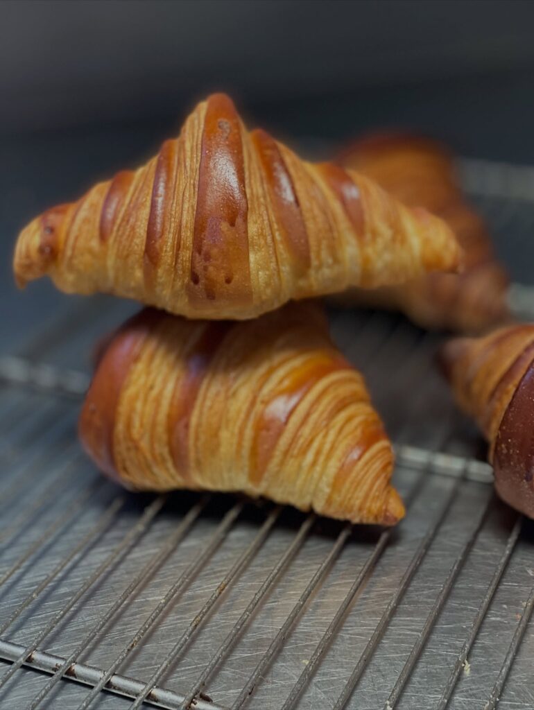 Freshly baked croissants cooling on a wire rack, showcasing golden, flaky layers, perfect for breakfast delights.