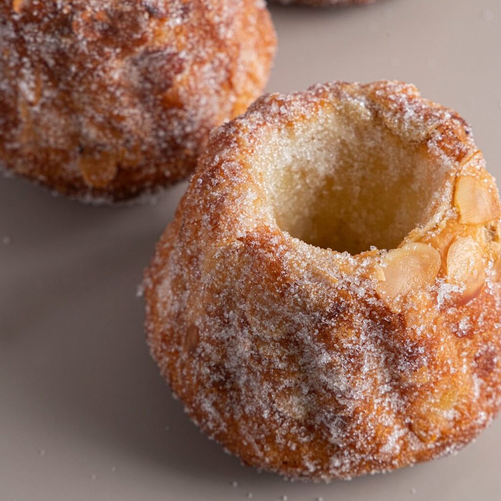 Sugar-coated bundt cakes with almonds on a table, highlighting texture and golden color.