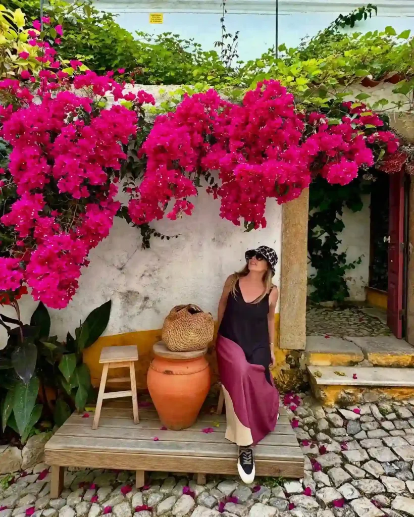 Relaxing woman in a garden with vibrant pink bougainvillea flowers and rustic decor, capturing serene outdoor vibes.