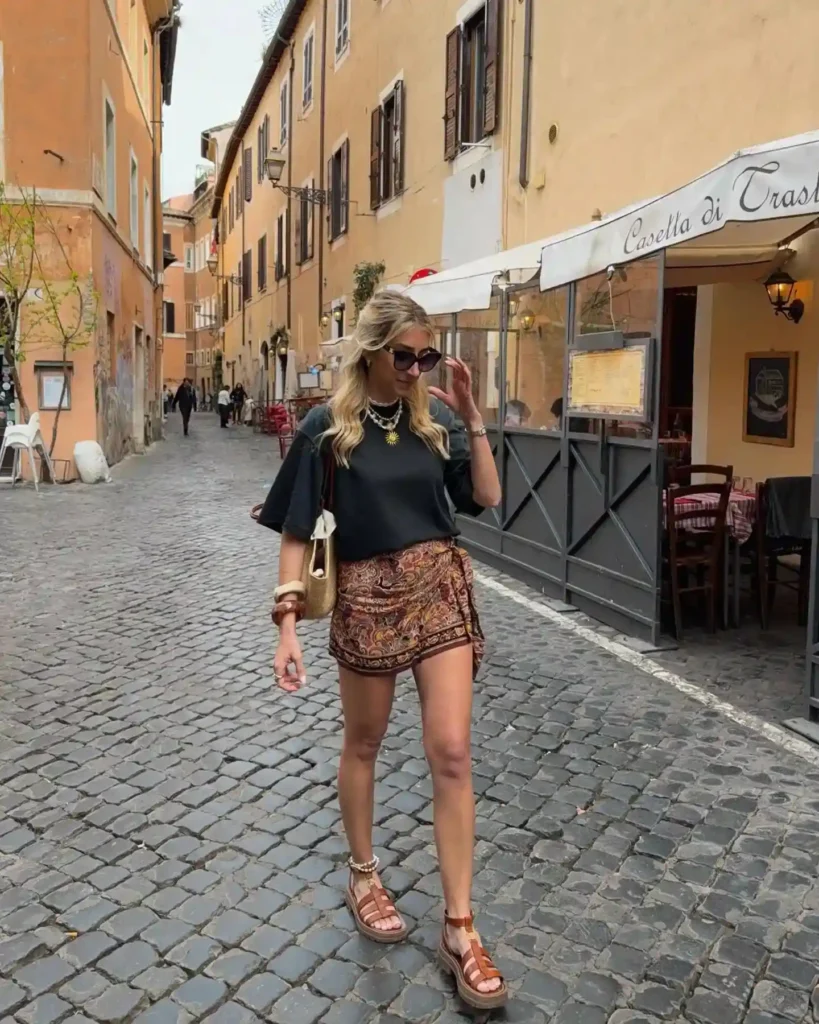 Woman walking in a stylish outfit down a cobblestone street in Rome, lined with charming shops and cafes.