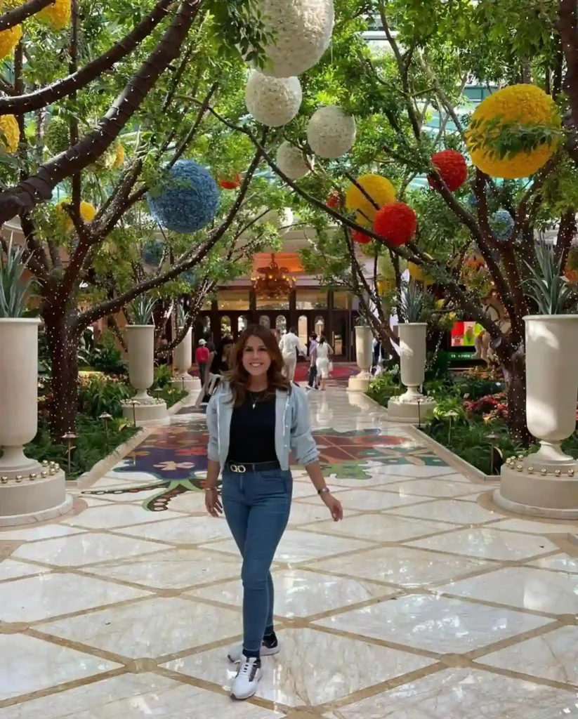 Person walking through a vibrant, decorated hotel corridor with colorful ornaments and lush greenery.