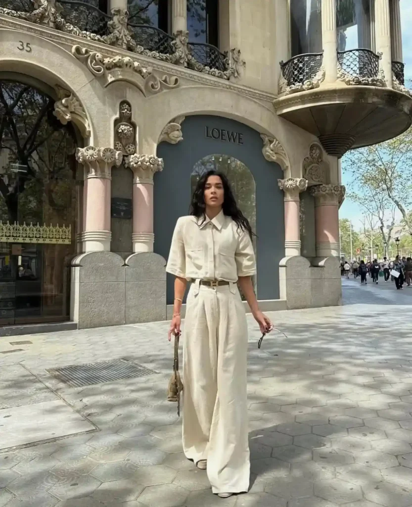 Woman in a stylish beige outfit poses confidently outside the Loewe store in a bustling urban setting.
