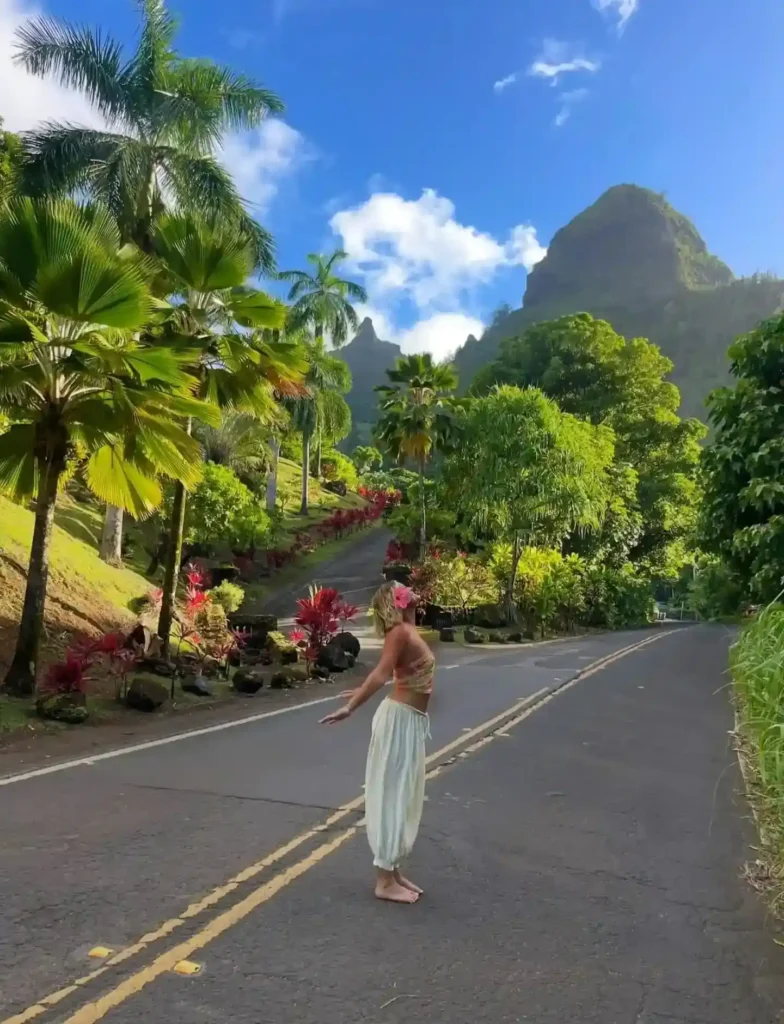 A joyful dancer in a tropical paradise, surrounded by lush greenery and majestic mountains under a blue sky.