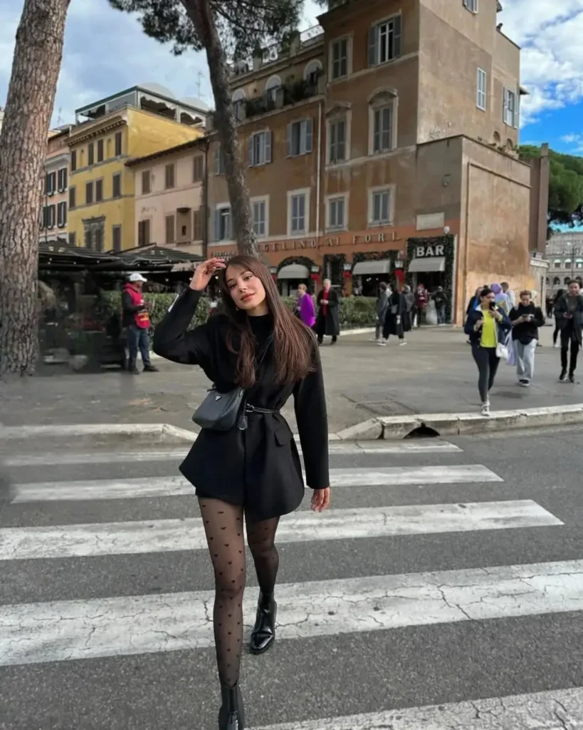 Stylish woman in black outfit crossing a street in a busy urban area, showcasing a vibrant city atmosphere.