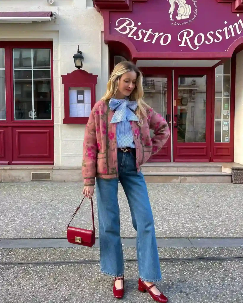 Fashionable woman in wide jeans and a floral jacket stands outside Bistro Rossini, showcasing Parisian street style.