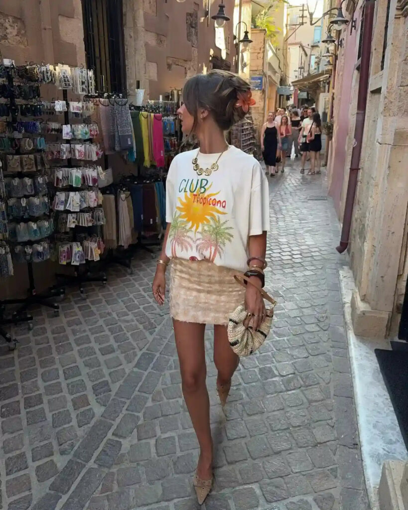 A stylish woman in a trendy outfit walks through a vibrant street market lined with colorful accessories.