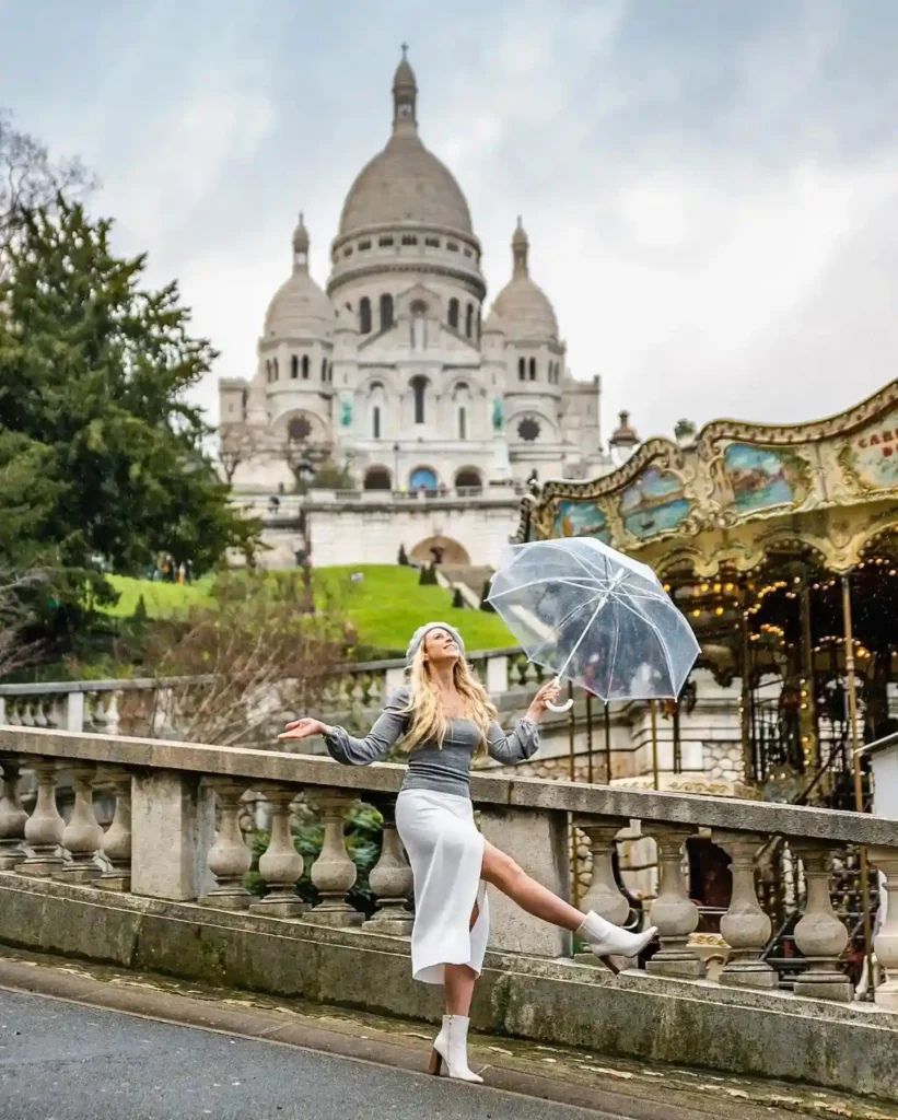 Woman with an umbrella poses joyfully in front of Sacré-Cœur Basilica, showcasing Parisian charm and style.