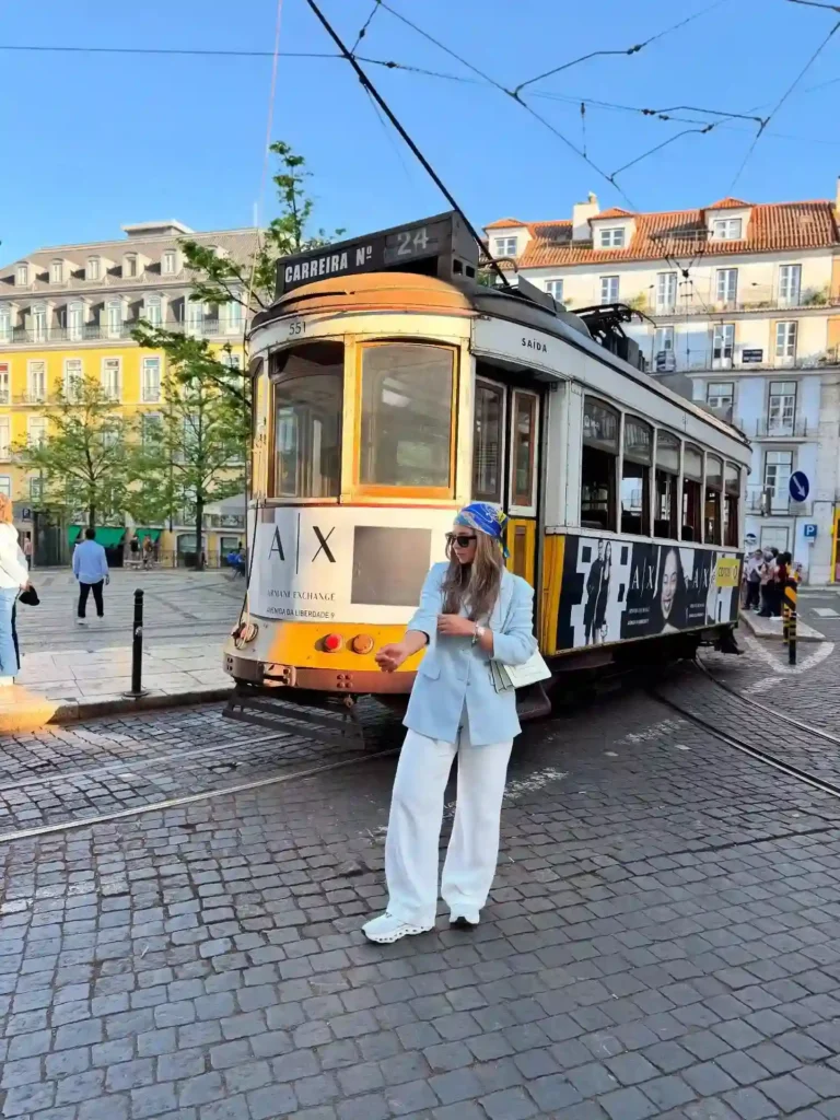 Tram 24 in Lisbon, with a fashionable woman in a light blue outfit standing on cobblestone streets.
