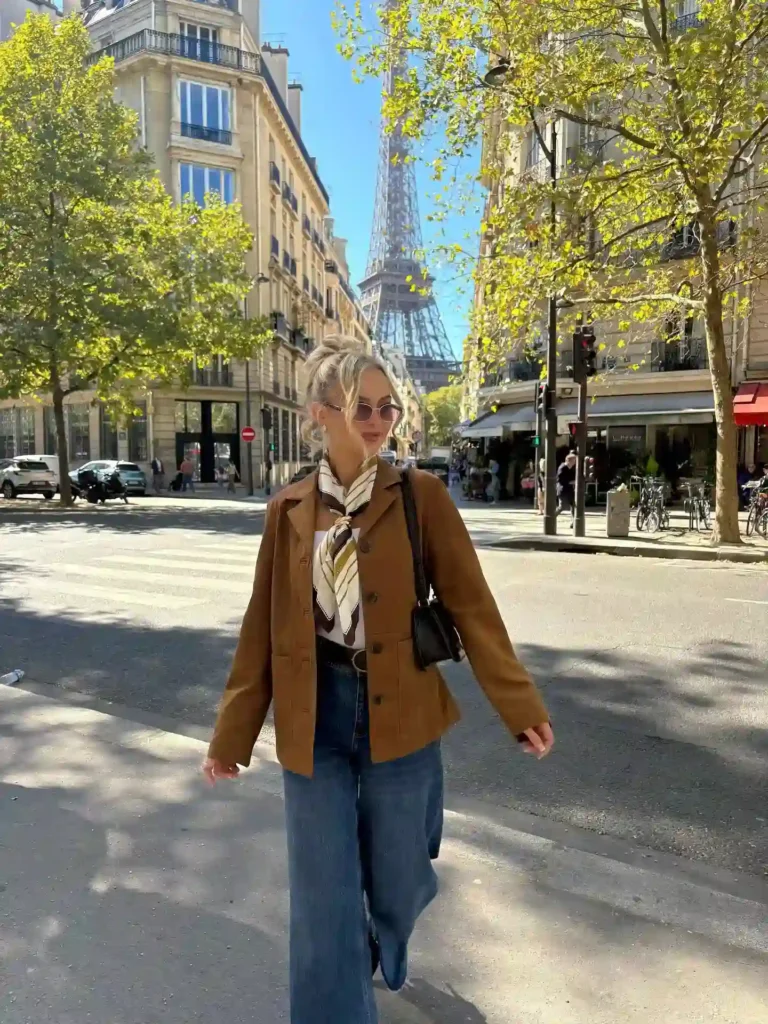 Stylish woman walking in Paris with the Eiffel Tower in the background, surrounded by autumn leaves and sunny skies.