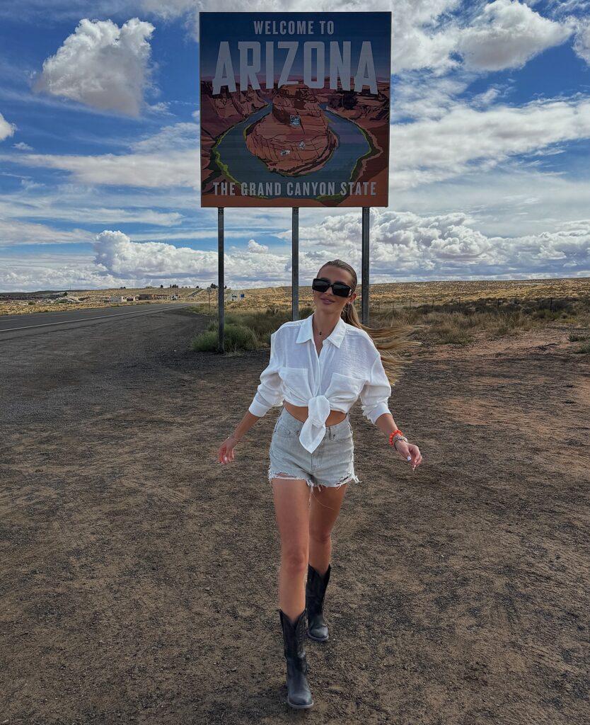 Person walking near Arizona state sign, showcasing the stunning landscapes of the Grand Canyon State.