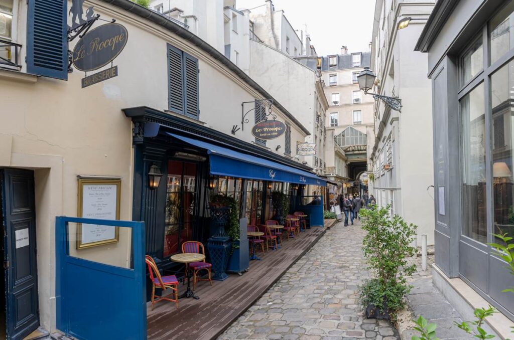 Charming Paris street with outdoor café seating, cobblestones, and classic architecture. Cozy European atmosphere.
