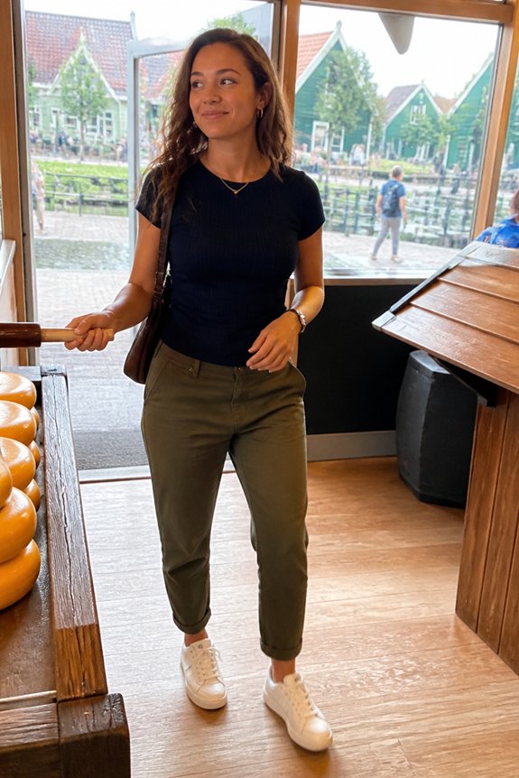 Woman in black tee and olive-green pants walks through a wooden shop with pumpkins; bright windows and outdoor scene behind.