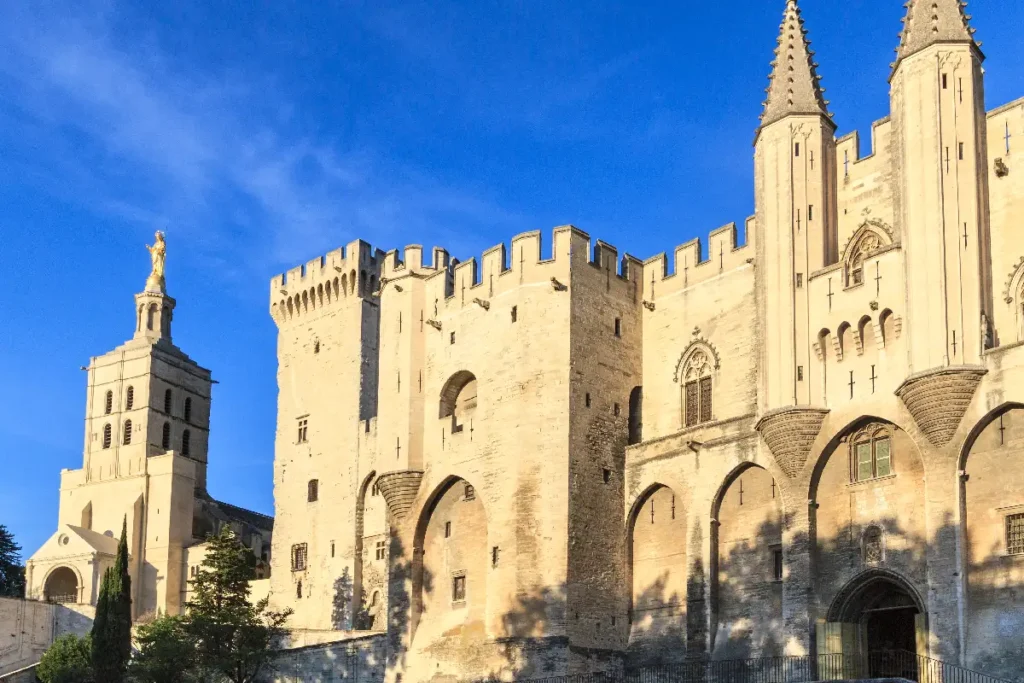 Historic Palais des Papes in Avignon, France, showcasing medieval architecture against a clear blue sky.