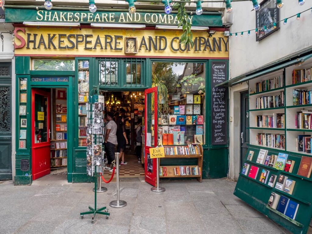 Iconic Shakespeare and Company bookstore in Paris, featuring colorful books and inviting open doors.