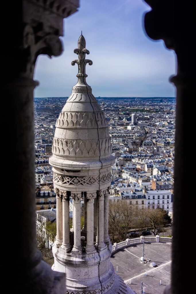 Intricate tower of Sacré-Cœur Basilica overlooking Paris cityscape on a clear day.