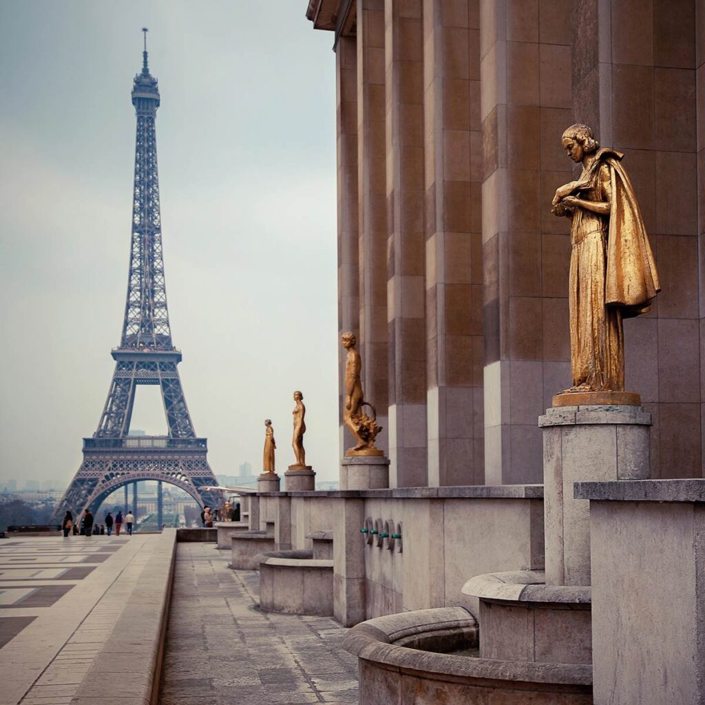 Golden statues at Trocadéro with Eiffel Tower in the background, Paris, showcasing iconic architecture and art.