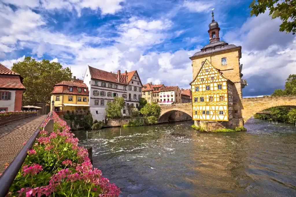 A picturesque view of a charming riverside town with colorful buildings and a historic bridge under a clear blue sky.