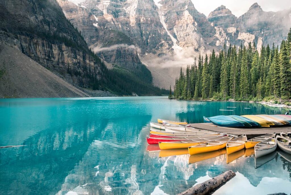 Colorful canoes on Moraine Lake with mountain and forest backdrop in Banff National Park.