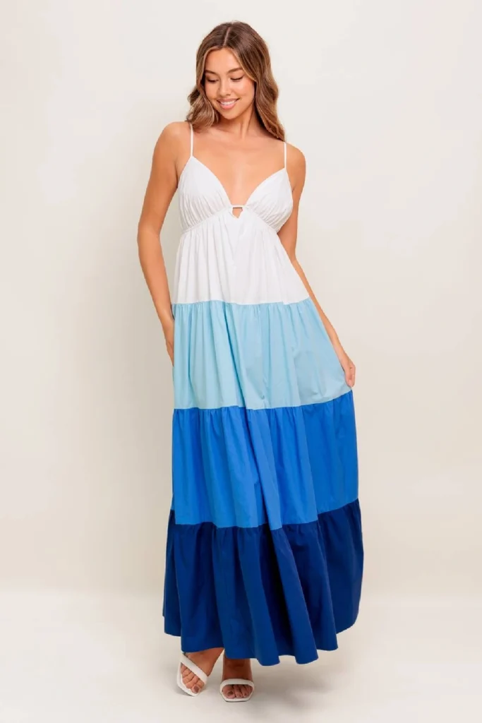 Smiling woman in a colorful tiered maxi dress featuring shades of blue and white, perfect for summer occasions.