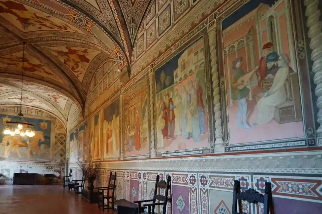 Ornate mural interior with intricate designs and historical scenes, showcasing decorative architecture and vintage seating.